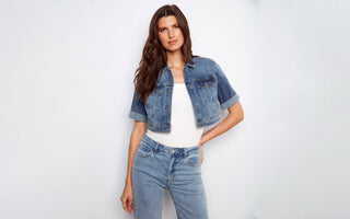 A woman wearing a cropped denim jacket with a white top and light wash jeans.