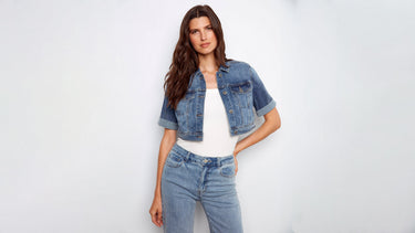 A woman wearing a cropped denim jacket with a white top and light wash jeans.