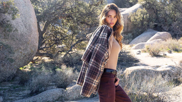 A woman carrying a plaid jacket over her shoulder in the desert