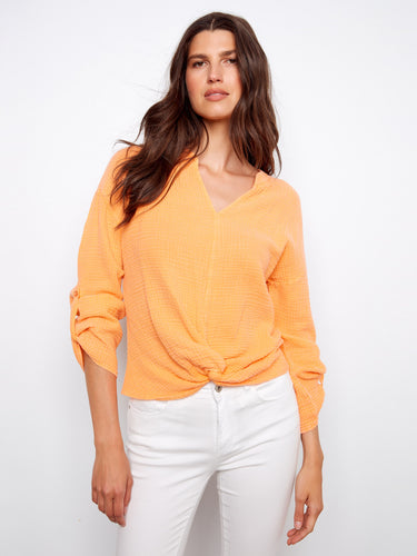 Vibrant orange shirt showcasing a unique front knot detail, designed in breathable 100% cotton material by Charlie B.