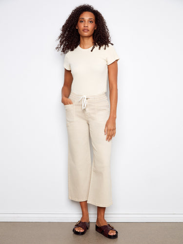 Beige wide-leg pants featuring a cropped length and drawstring waist, paired with casual sandals by Charlie B.