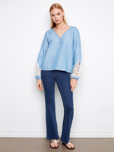 Chic blue top adorned with openwork lace on the sleeves, adding a touch of sophistication to any outfit. By Charlie B.