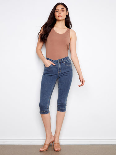 Model in medium blue capri jeans featuring a sleek slim fit and knee length. Crafted with stretch denim for comfort by Charlie B.