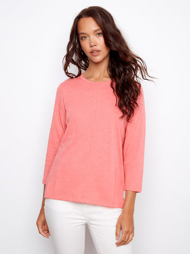 Coral top with a flattering crew neckline, paired with white pants. Perfect for casual outings. Designed by Charlie B.