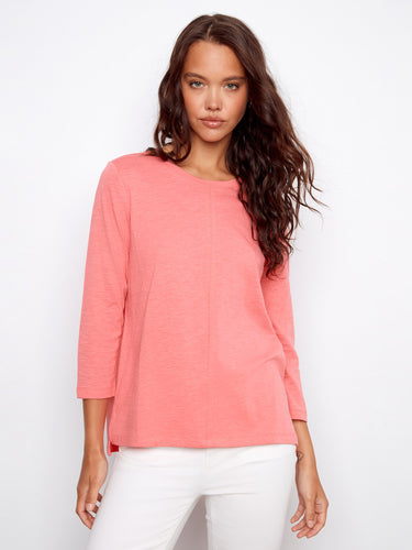 Elegant coral top showcasing 3/4 sleeves, ideal for versatile styling. Complements white pants beautifully. By Charlie B.