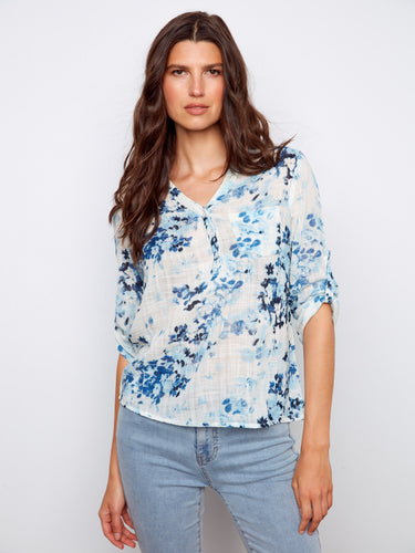 Floral blouse with a Henley neckline, showcasing a blend of blue and white hues. Perfect for casual outings. By Charlie B.