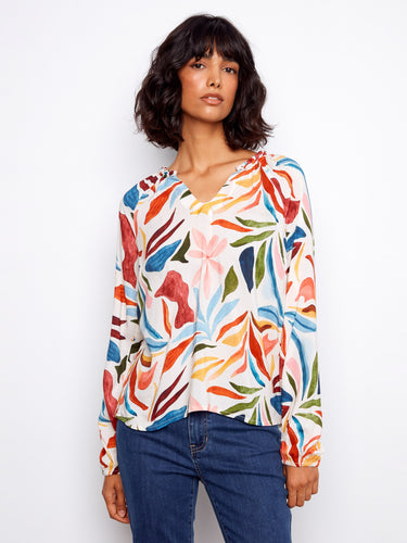Colorful blouse with a notched neckline and vibrant floral pattern, featuring unique braided collar detail. By Charlie B.