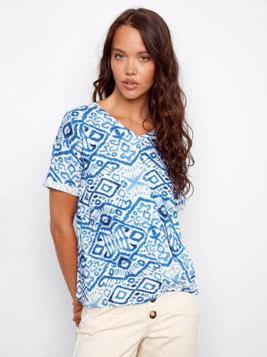 Patterned top showcasing short sleeves in a vibrant blue design, matched with light-colored pants for comfort by Charlie B.