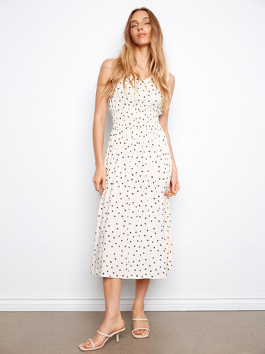 White dress with black polka dots, featuring a wide strap design and smocked waist by Charlie B.
