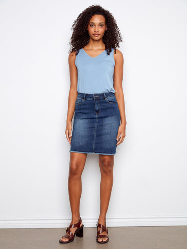 Denim skirt featuring a regular rise for comfortable wear, paired with a sleeveless top. Finished with frayed edges. By Charlie B.