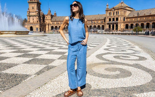 Woman in a chambray sleeveless jumpsuit and sunglasses standing in Plaza de España, Seville.