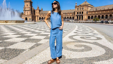 Woman in a chambray sleeveless jumpsuit and sunglasses standing in Plaza de España, Seville.