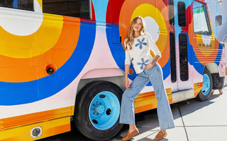 Blonde model in a white floral-embroidered sweater and light-wash flare jeans from Charlie B, styled with brown loafers.