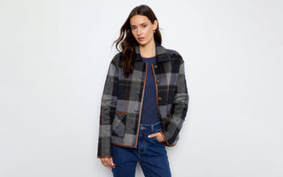 A woman wearing a grey plaid jacket with faux leather trim 