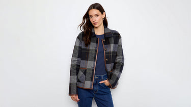 A woman wearing a grey plaid jacket with faux leather trim 
