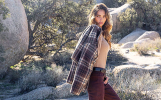 A woman carrying a plaid jacket over her shoulder in the desert