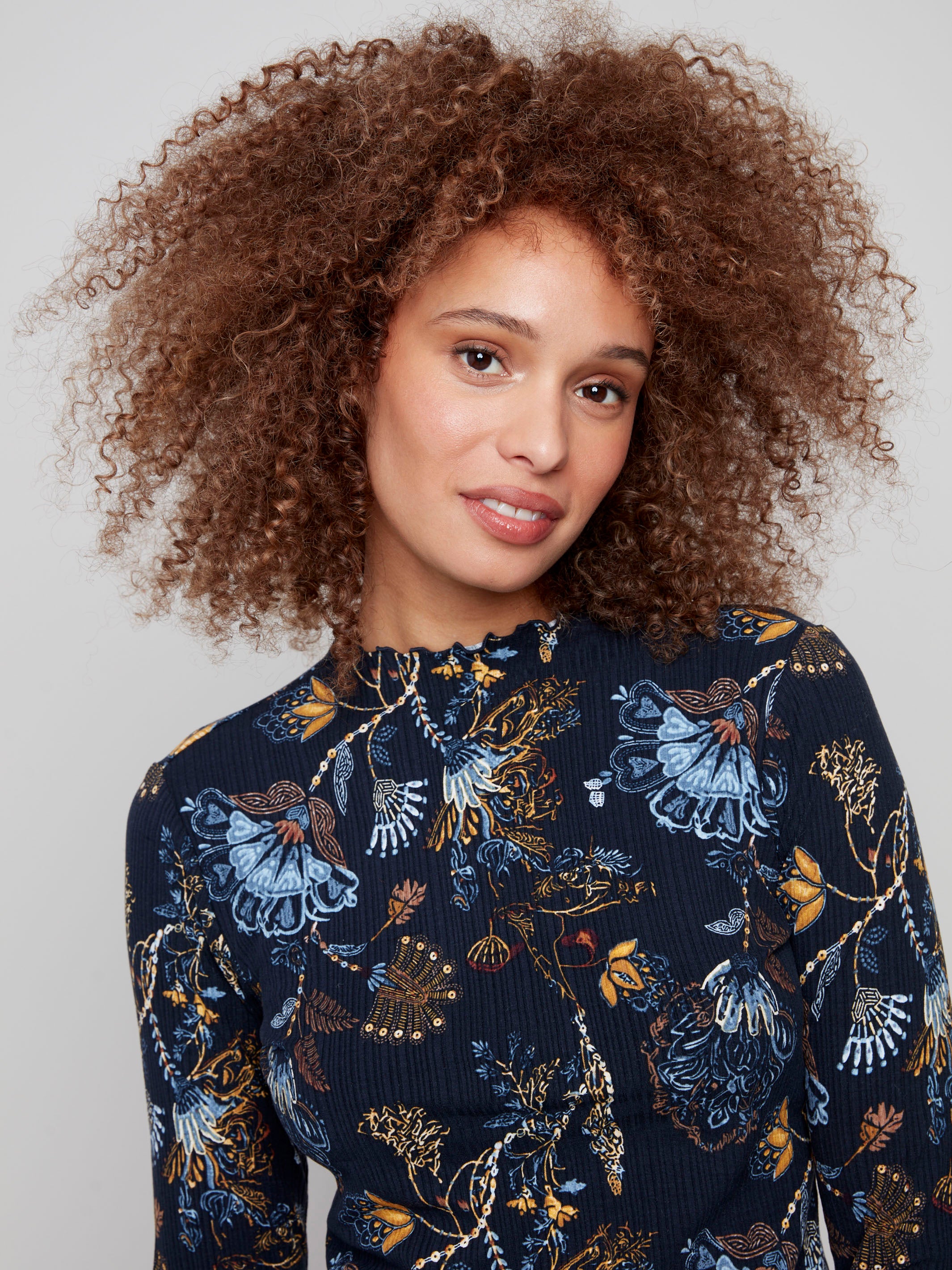 Stylish top with delicate ruffle accents at the hem and cuffs, offering a sophisticated yet playful look by Charlie B.