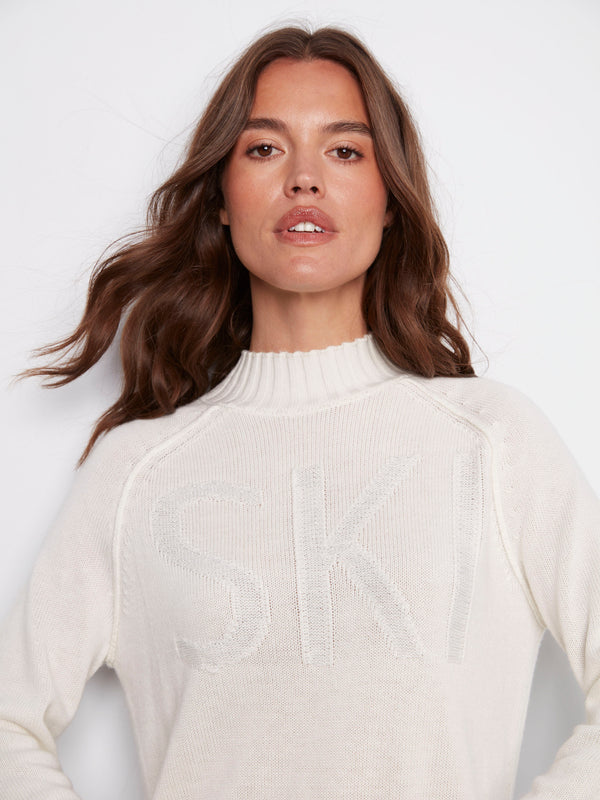 This chic ecru sweater showcases a bold 'SKI' jacquard pattern with raglan sleeves, offering both style and comfort by Charlie B.