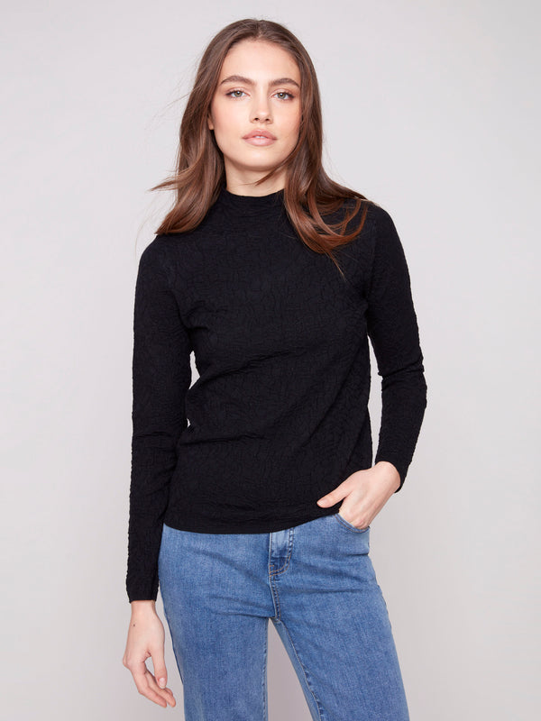 Black slim fit sweater paired with blue jeans, showcasing a stylish mock neck by Charlie B.