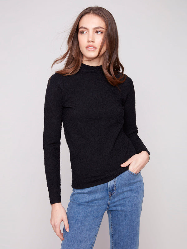 Textured black sweater with blue jeans, highlighting its elegant slim fit design by Charlie B.