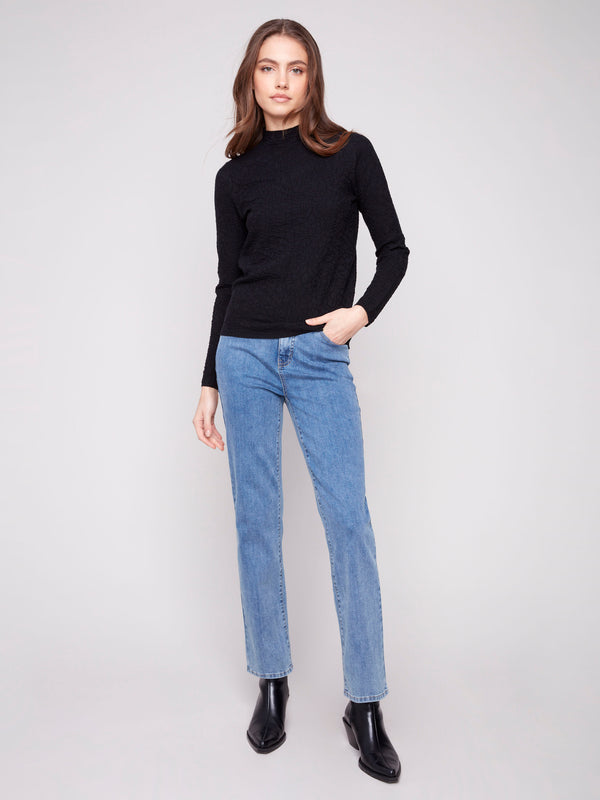Long-sleeve black sweater in textured fabric styled with casual blue jeans by Charlie B.