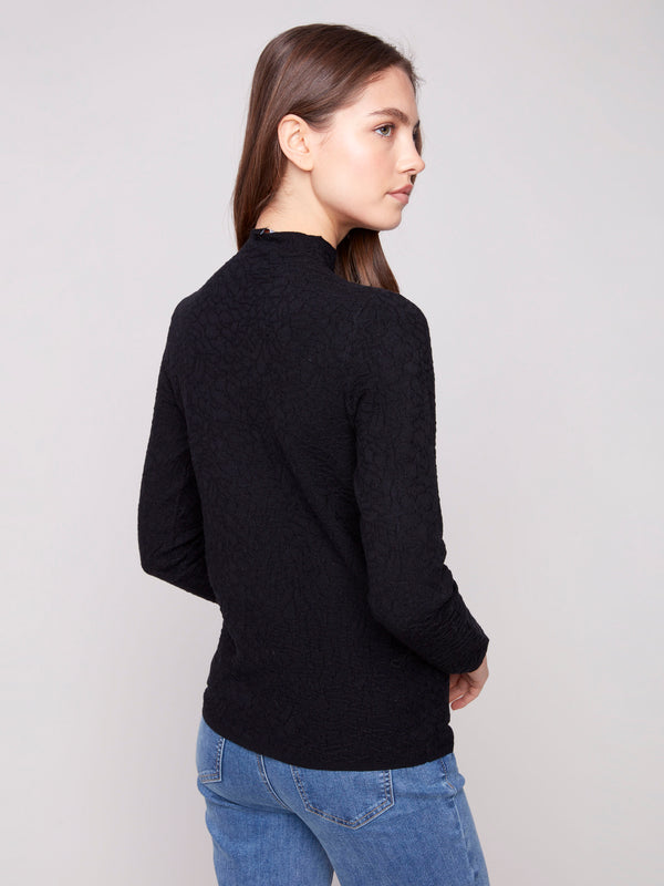 Elegant mock neck black sweater combined with blue denim for a chic look by Charlie B.