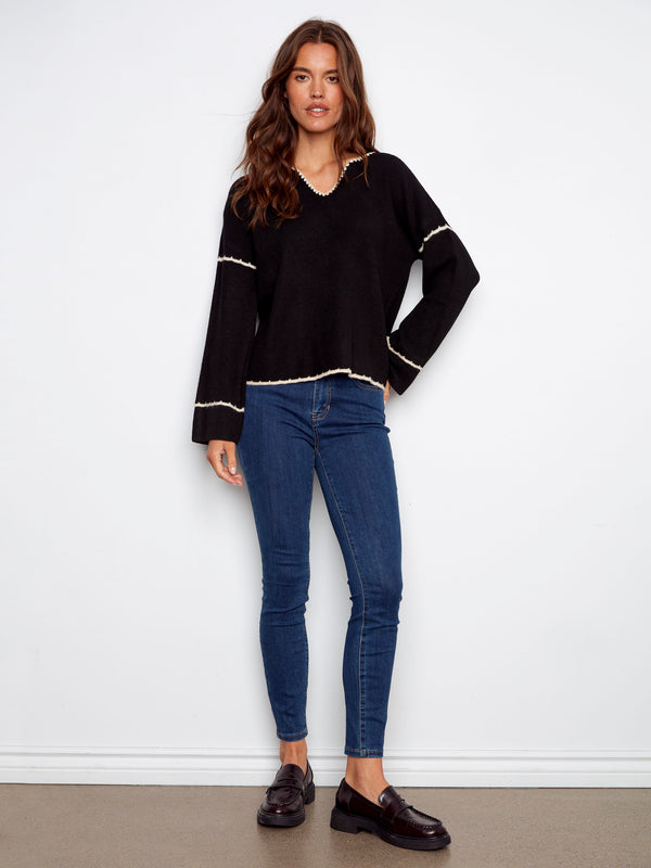 Chic black sweater showcasing a relaxed fit and delicate white embroidery accents by Charlie B.