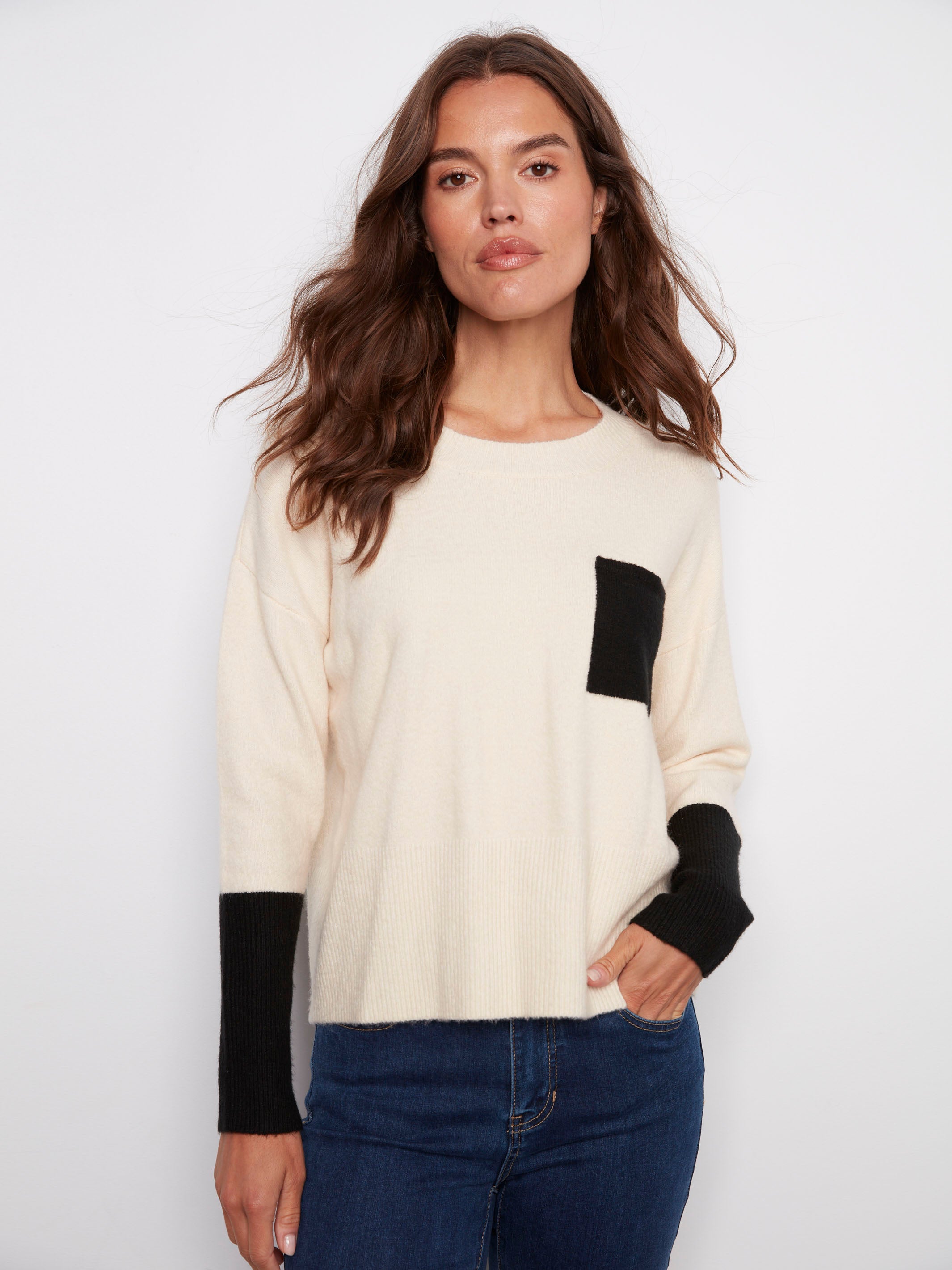 Ecru sweater featuring a classic crew neck design, highlighted by its stylish contrast black pocket by Charlie B.