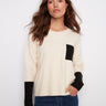 Ecru sweater featuring a classic crew neck design, highlighted by its stylish contrast black pocket by Charlie B.