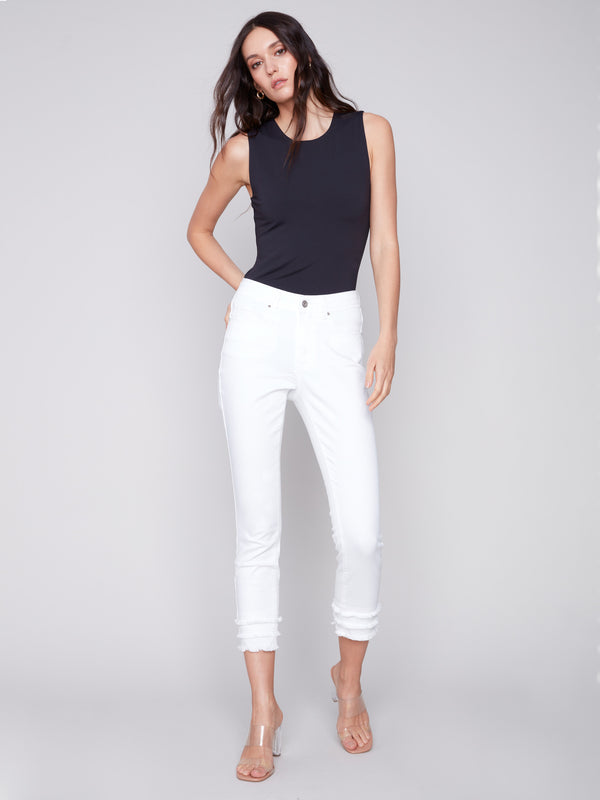 Regular rise waist white pants with skinny fit and modern frayed hem detail by Charlie B.