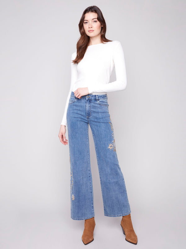 Medium blue jeans featuring a five-pocket design and floral embroidery for a chic look by Charlie B.
