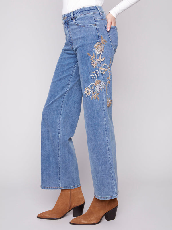 Embroidered flowers adorn these long-length denim jeans, adding elegance by Charlie B.