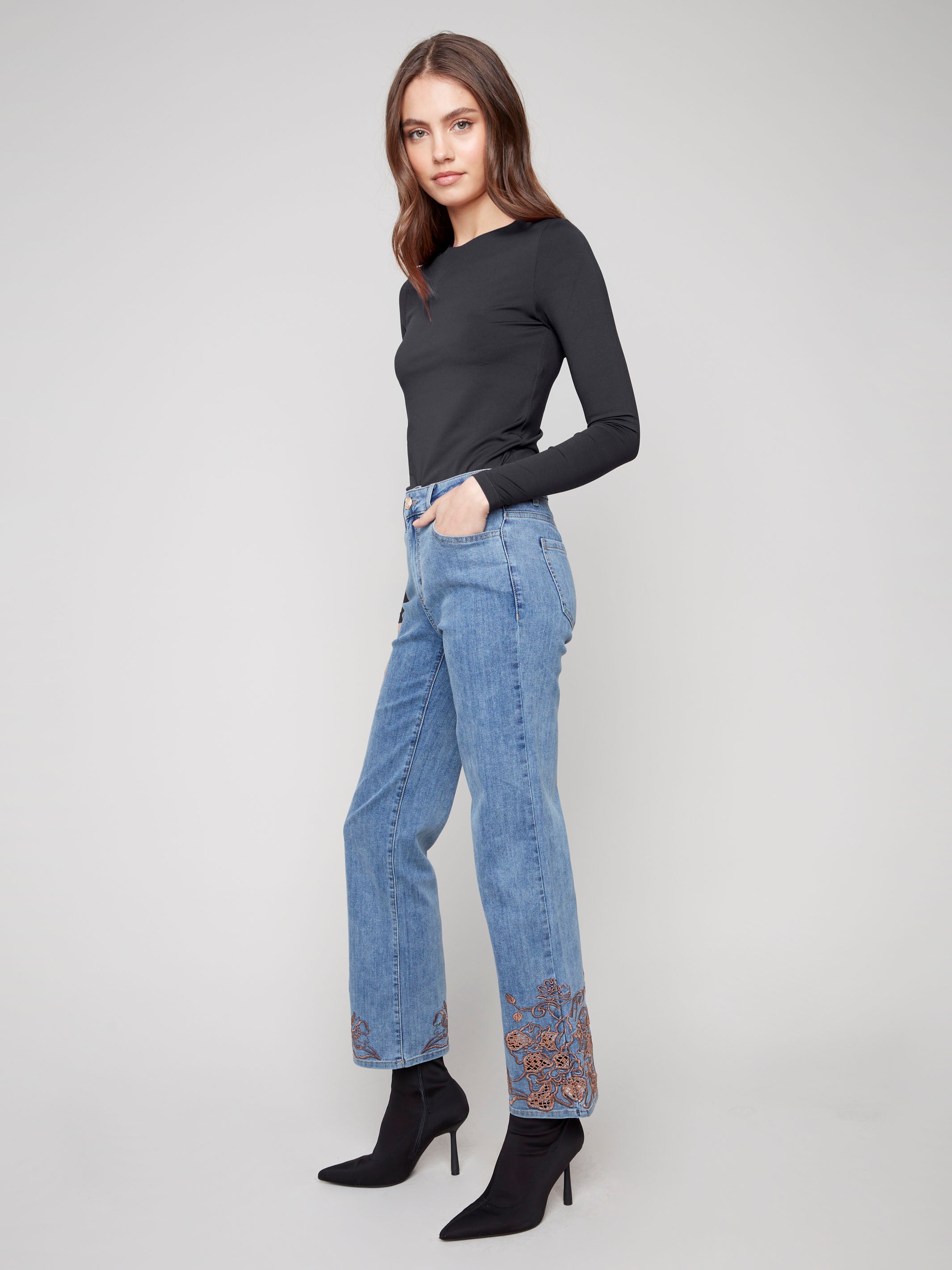 These jeans showcase exquisite lace embroidery at the hem, enhancing the classic straight-leg silhouette for a chic look by Charlie B.