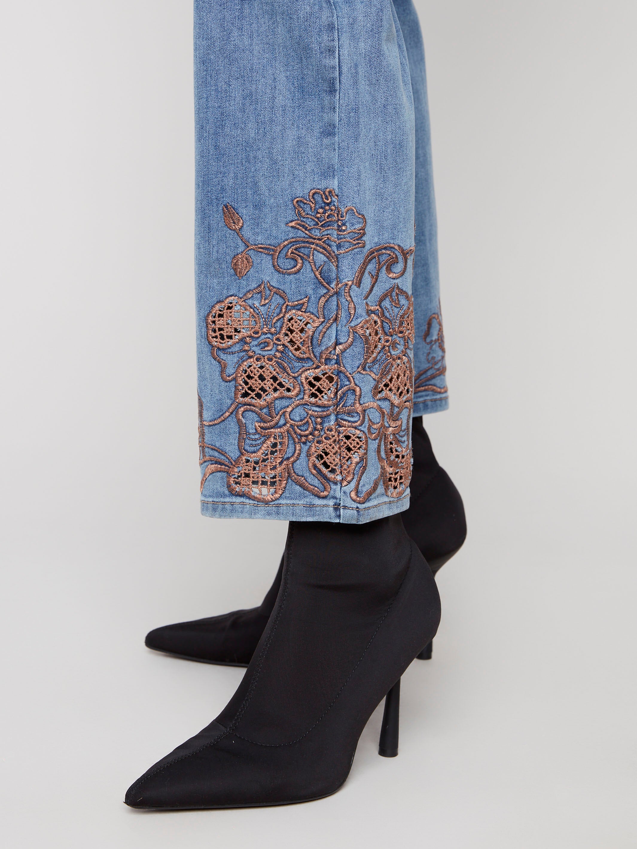 Stylish medium blue denim pants crafted from stretch fabric, ensuring ease of movement and adorned with intricate lace patterns by Charlie B.