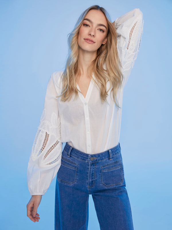 Intricate sleeve embroidery elevates this chic white blouse by Charlie B.