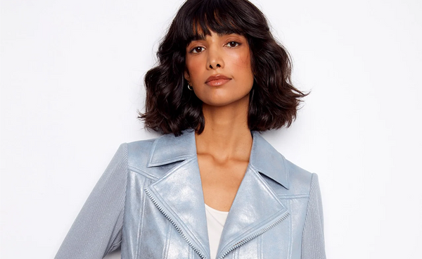 A woman with wavy bangs wearing a light blue suede moto jacket with a notch lapel.