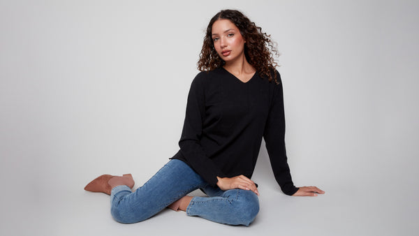 Versatile black sweater showcasing elegant side slits on the hem, ideal for layering or standalone wear by Charlie B.