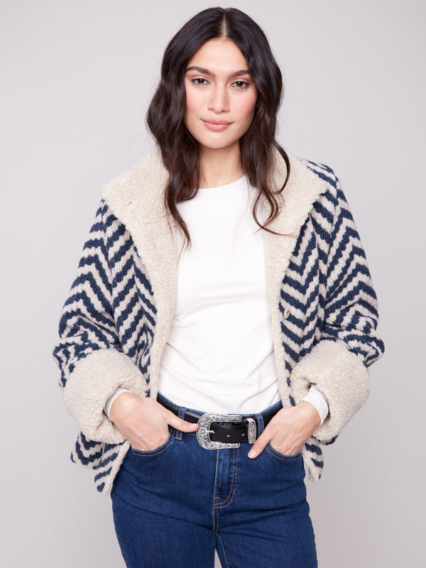 Navy Chevron Boucle Jacket featuring faux sherpa trim on collar and cuffs, adding an elegant touch to its chic pattern by Charlie B.
