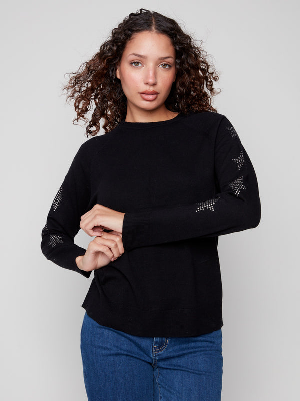 Stylish black sweater showcasing raglan sleeves and star studded accents on the arms by Charlie B.