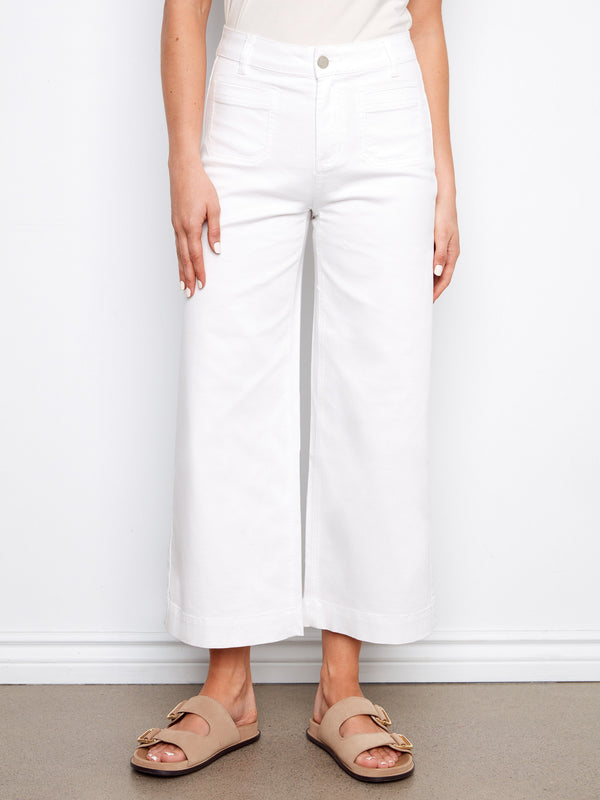 White cropped flare twill pants in stretch twill fabric, elegantly worn by a model by Charlie B.