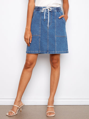 This denim skirt includes an elastic drawstring waistband, ensuring a comfortable and adjustable fit. By Charlie B.