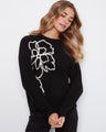 Black sweater featuring a crew neckline and floral design, paired with dark pants, perfect for a casual outing by Charlie B.