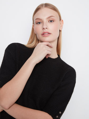 Elevate your style with floral button details at the cuffs of this black sweater by Charlie B.