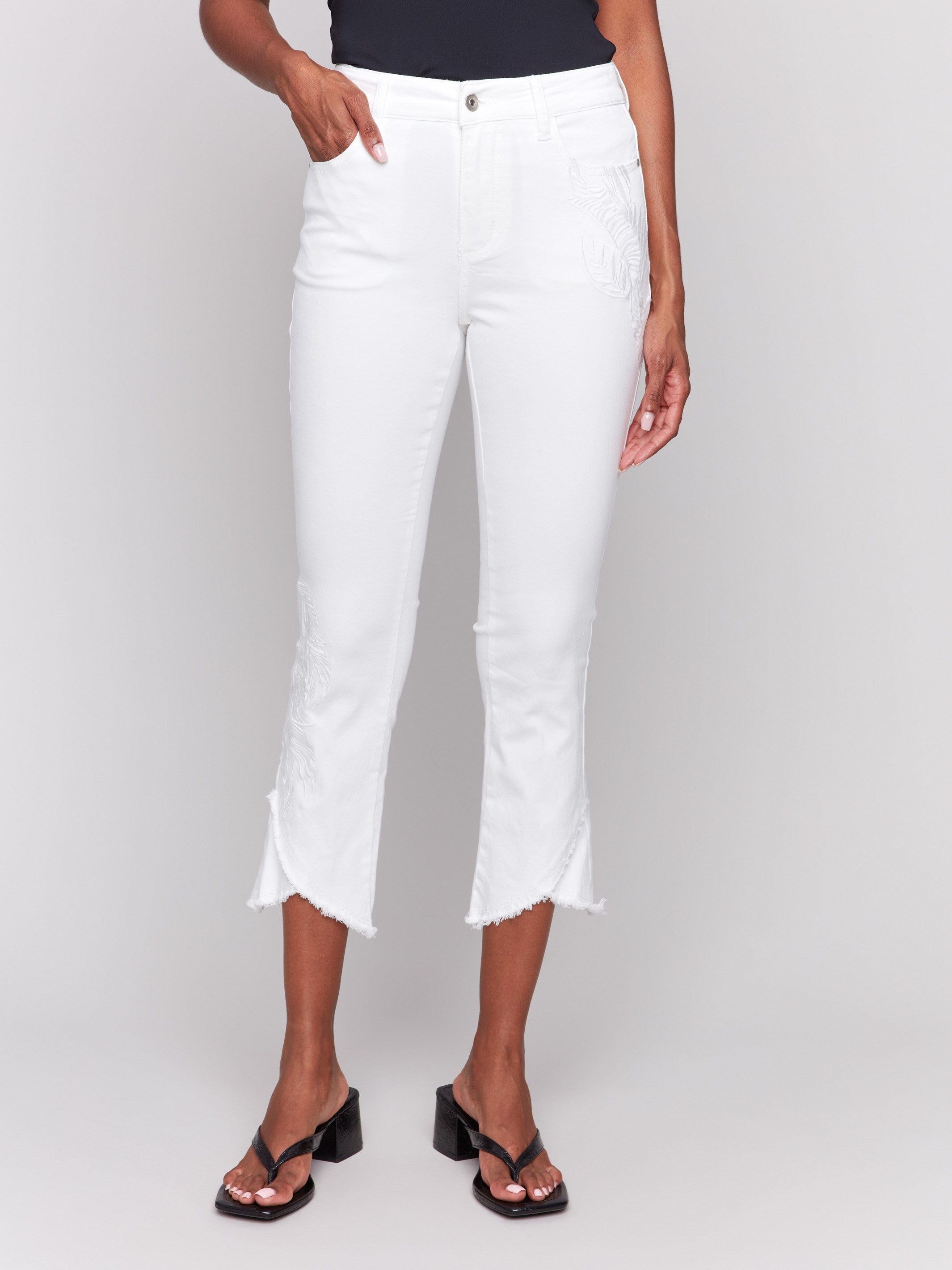 Cropped white pants featuring a five-pocket design and unique embroidered accents by Charlie B.