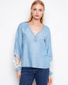 Light blue blouse with a braided V-neck and decorative buttons, featuring elegant balloon sleeves for a stylish look. By Charlie B.