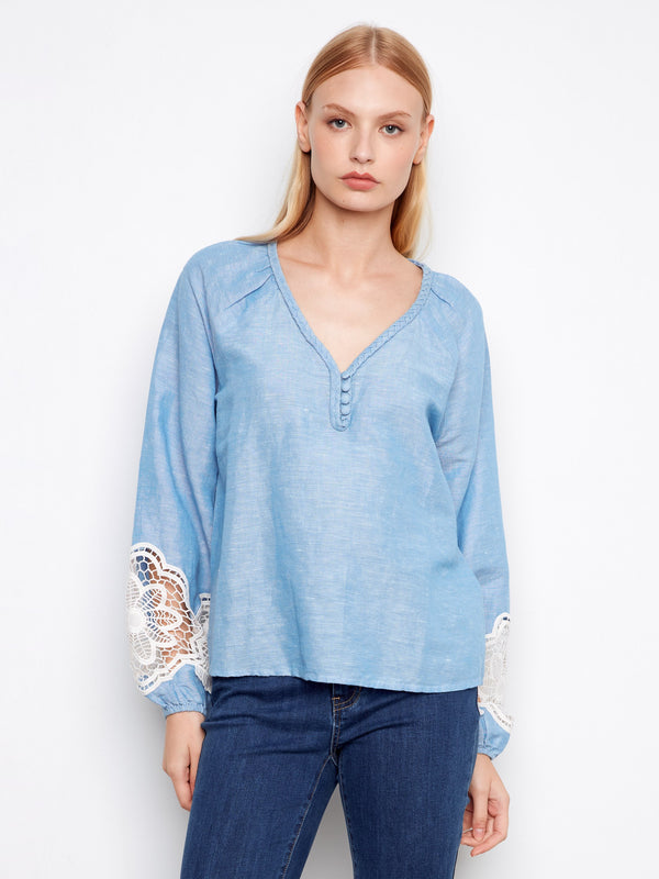 Light blue blouse with a braided V-neck and decorative buttons, featuring elegant balloon sleeves for a stylish look. By Charlie B.