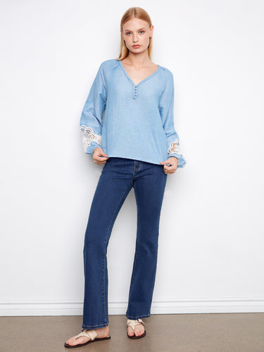 Blue blouse designed with a braided V-neck and eye-catching balloon sleeves, offering both comfort and style. By Charlie B.