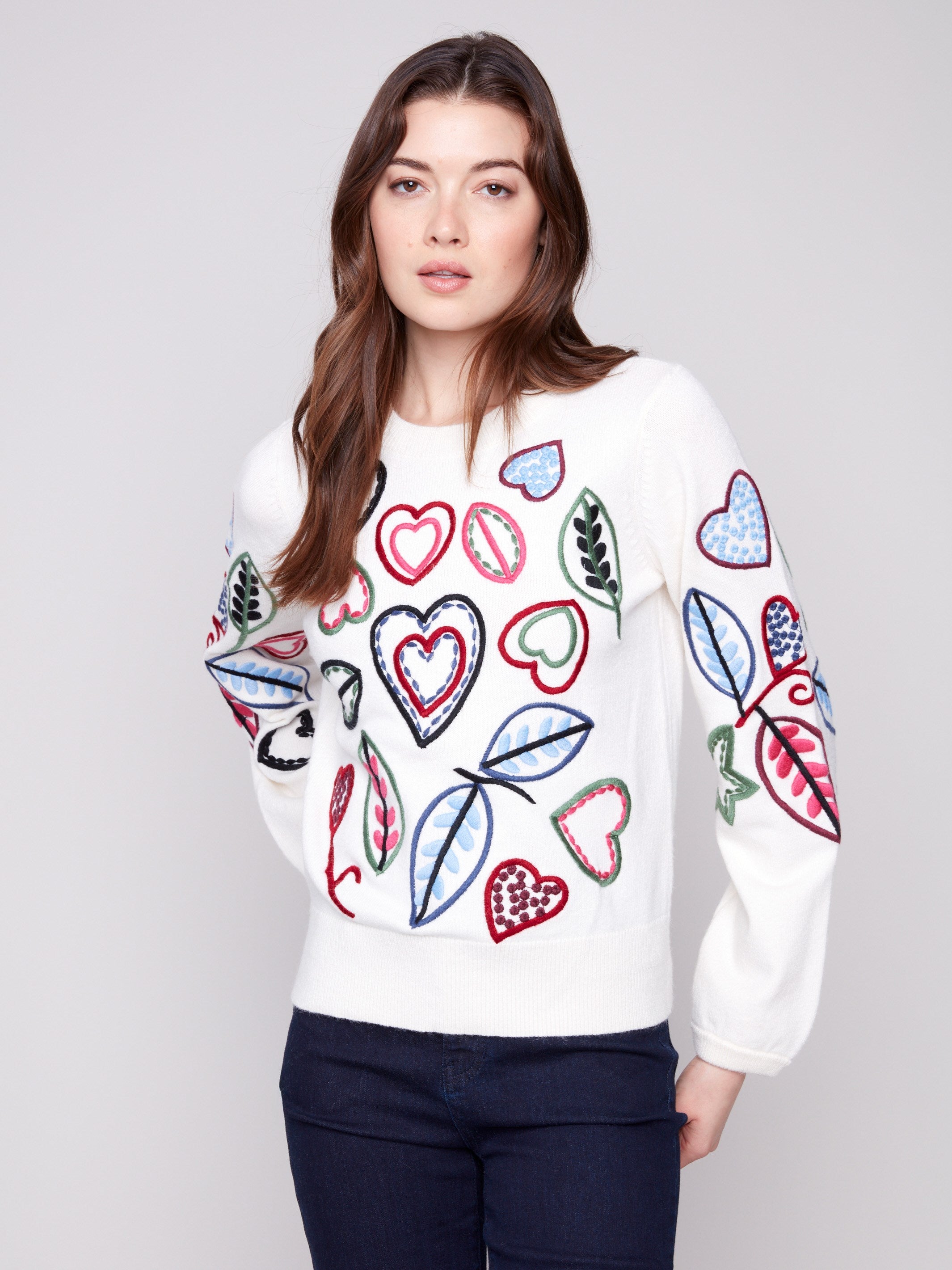 Ecru sweater adorned with colorful embroidery of hearts and leaves, showcasing a relaxed fit design by Charlie B.