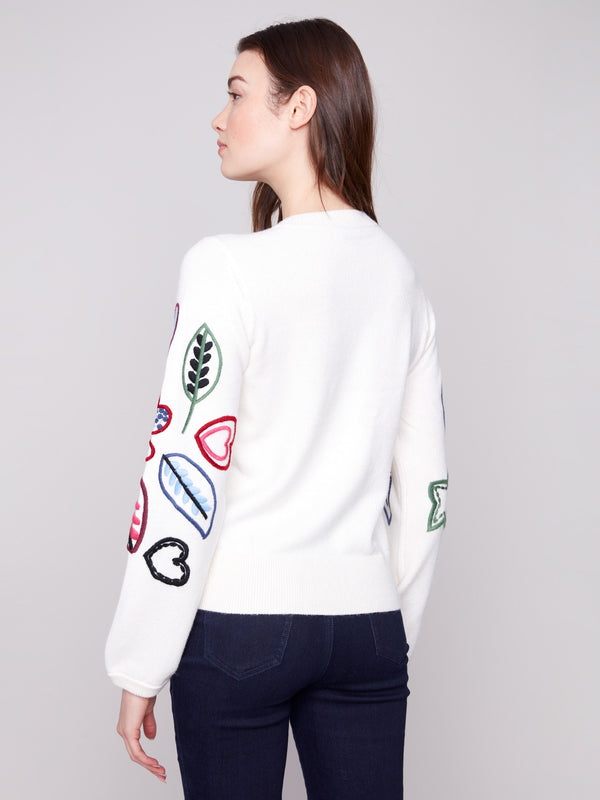 Ecru sweater decorated with multicolored heart and leaf patterns, offering a comfortable relaxed fit by Charlie B.