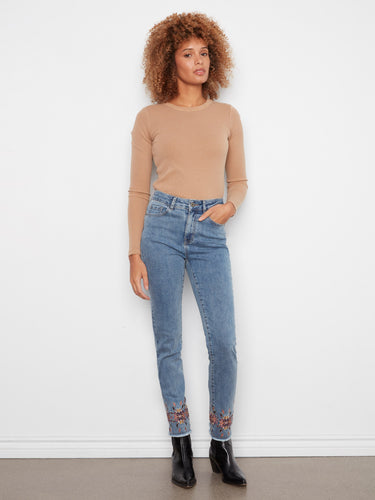 Medium blue slim leg jeans with stretch denim and intricate embroidery at the hem, complete with a button closure by Charlie B.